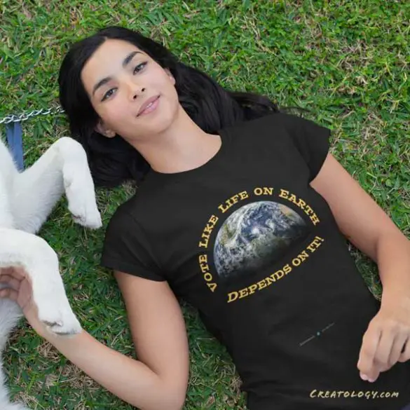 An EarthMart t-shirt with the message, ‘Vote Like Life on Earth Depends on It,’ is modeled by a female model relaxing with her dog. [Merch for sale in the EarthMart store at Redbubble]